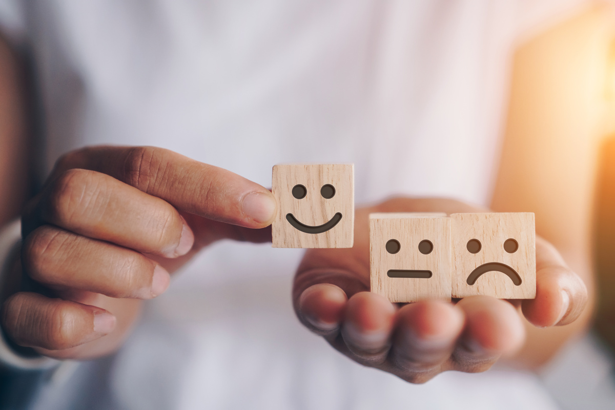 Person's Hands Holding Wooden Cubes with Various Emotions
